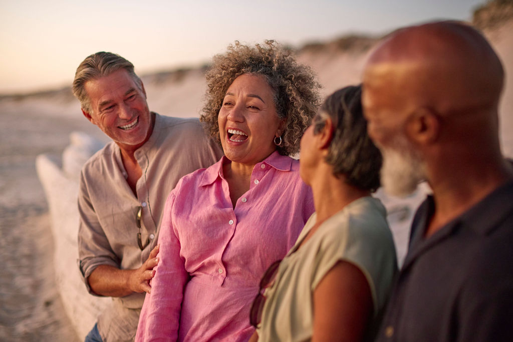 Friends laughing together on the coast at sunset