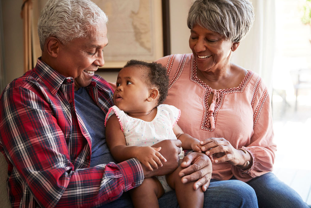 Grandparents holding their infant grandchild at home