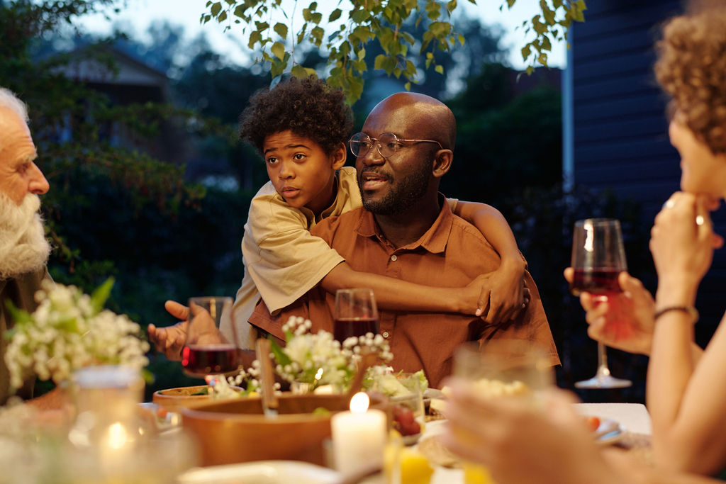 A family of several generations around an outdoor dinner table at dusk